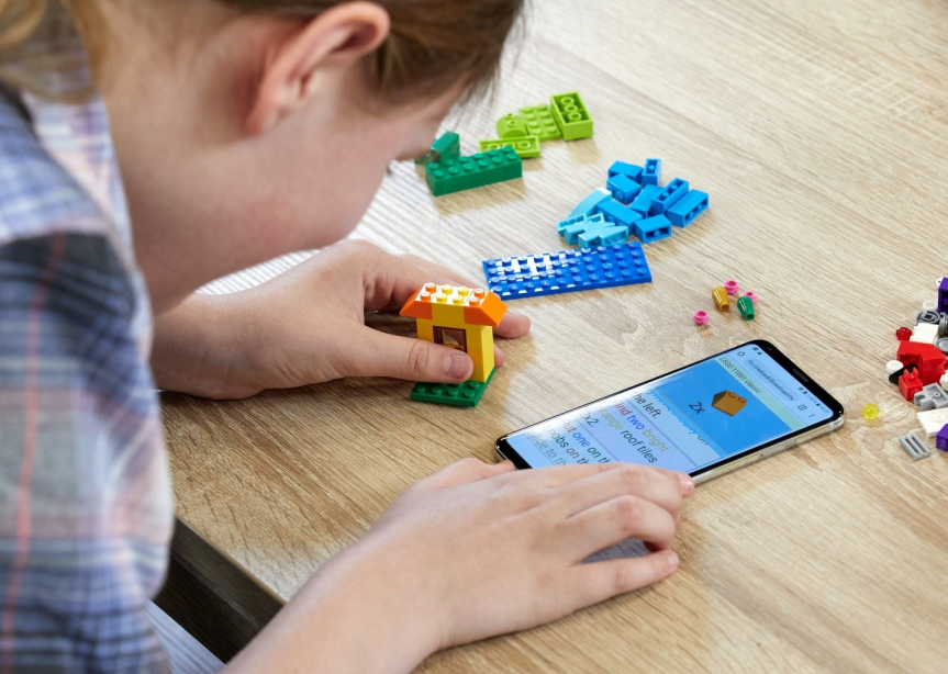 A blind child uses an OFAI-developed mobile phone app to help assemble a Lego kit